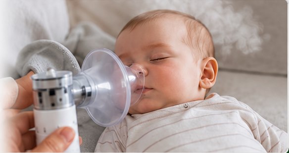 Baby sleeping while a nebulizer mask is held nearby